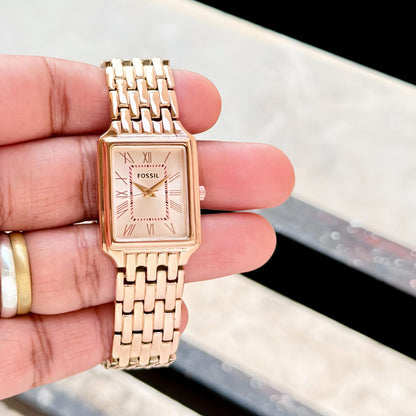 Rose gold Fossil watch held in a hand with a blurred background